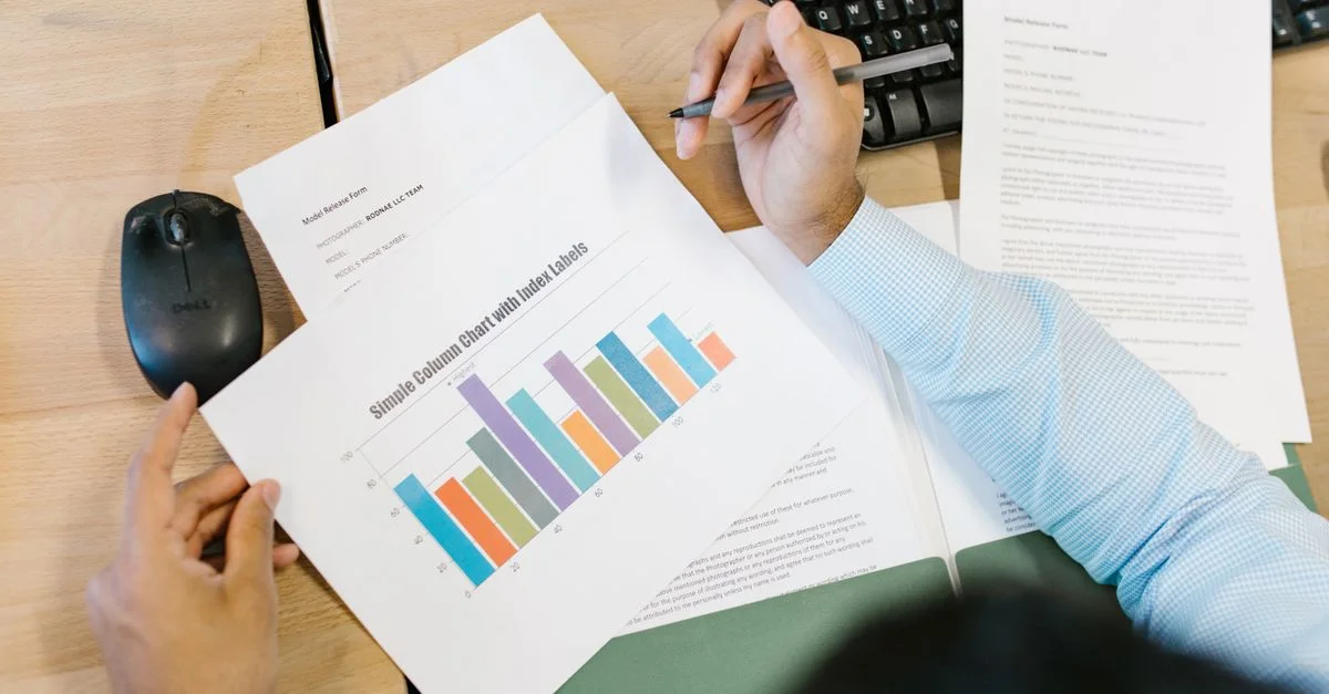 Un analyste d'affaires examine un graphique à barres coloré et des documents sur un bureau, indiquant une analyse de données.