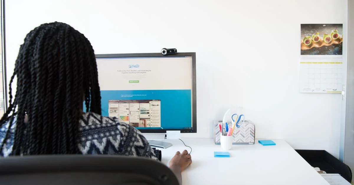 Une femme se concentre sur son ordinateur dans un environnement de bureau moderne. Cadre lumineux et minimaliste.