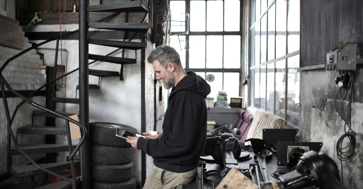Mécanicien professionnel utilisant une tablette dans un atelier industriel avec des outils
