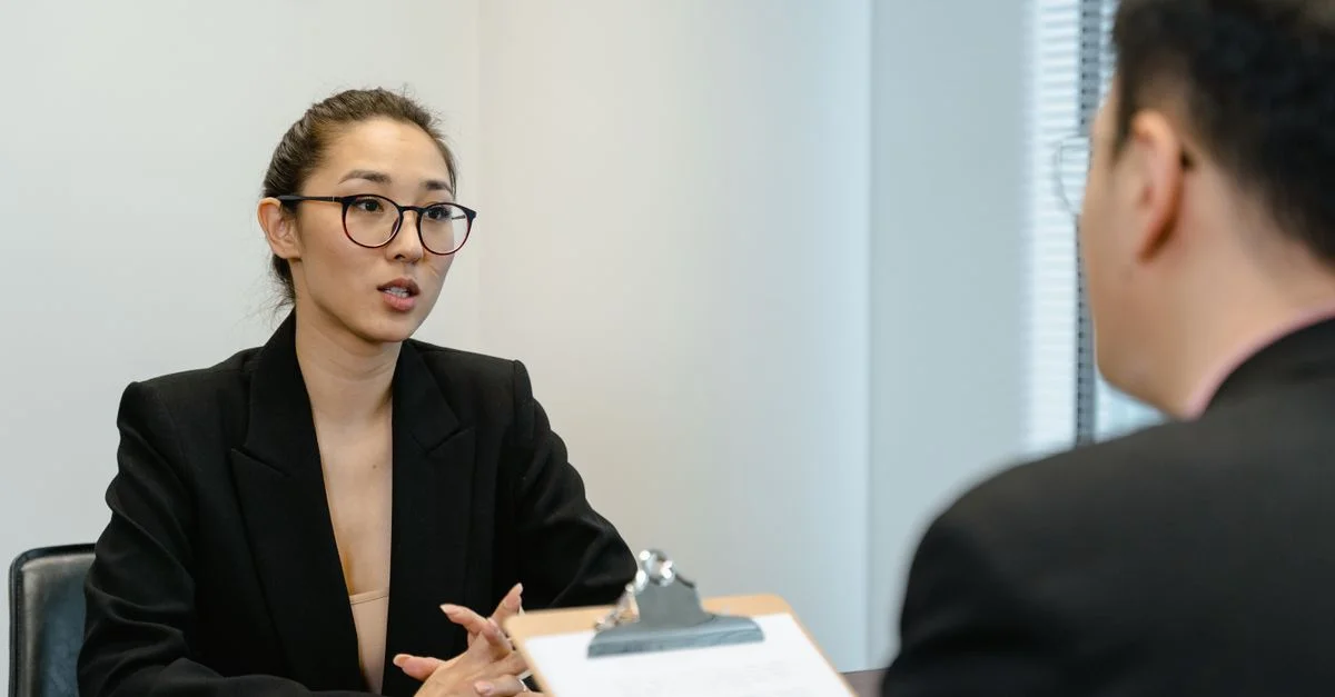 Une scène d'entretien concentrée dans un environnement de bureau avec une tenue professionnelle et un bloc-notes.