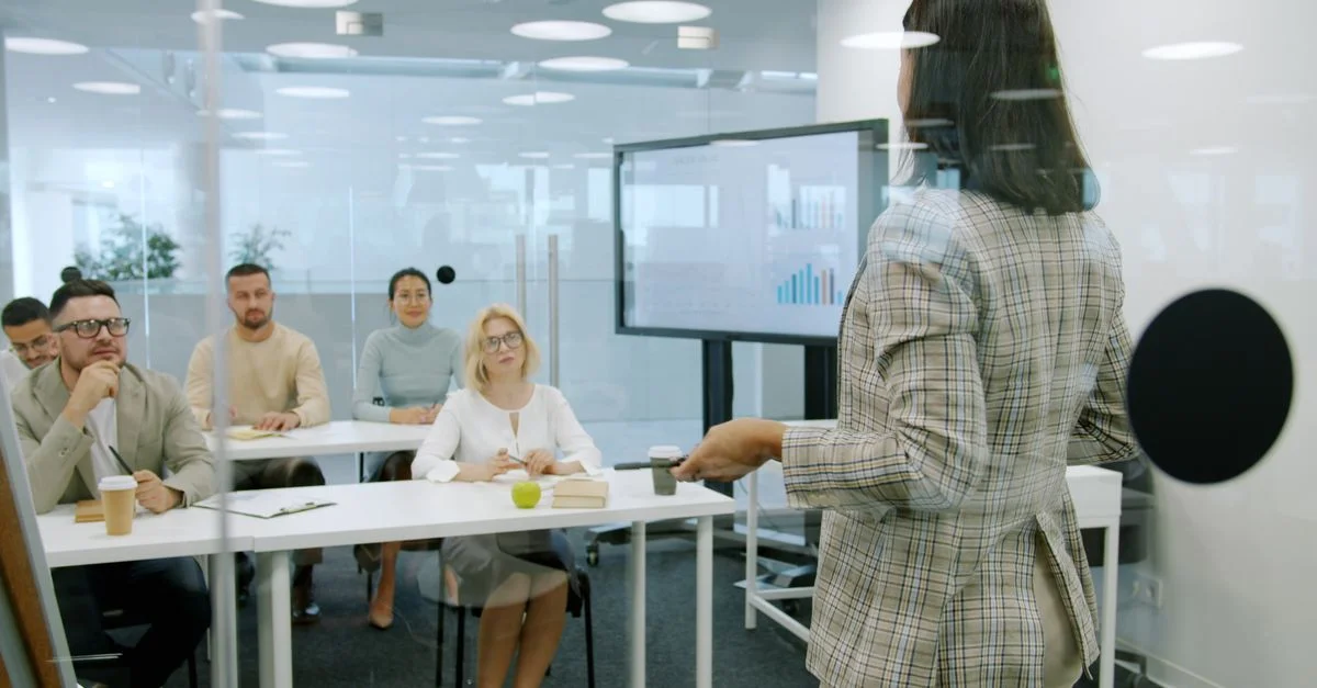 Femme d'affaires présentant un exposé à un public attentif dans un bureau moderne.