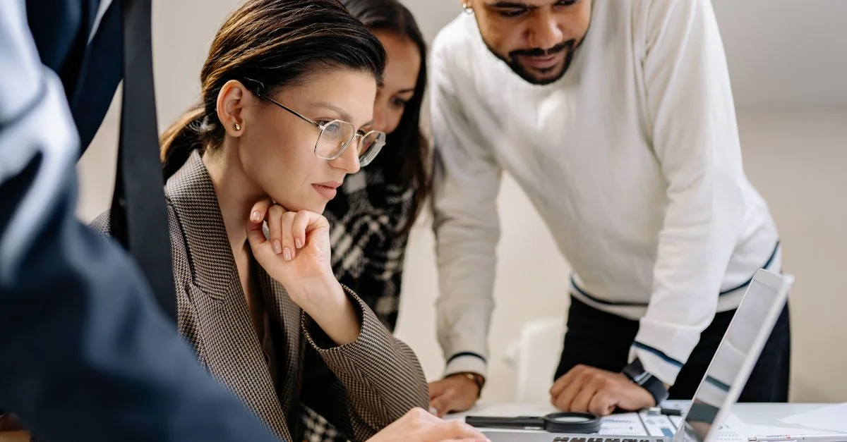 Groupe de professionnels collaborant sur un projet à un bureau avec des ordinateurs portables.
