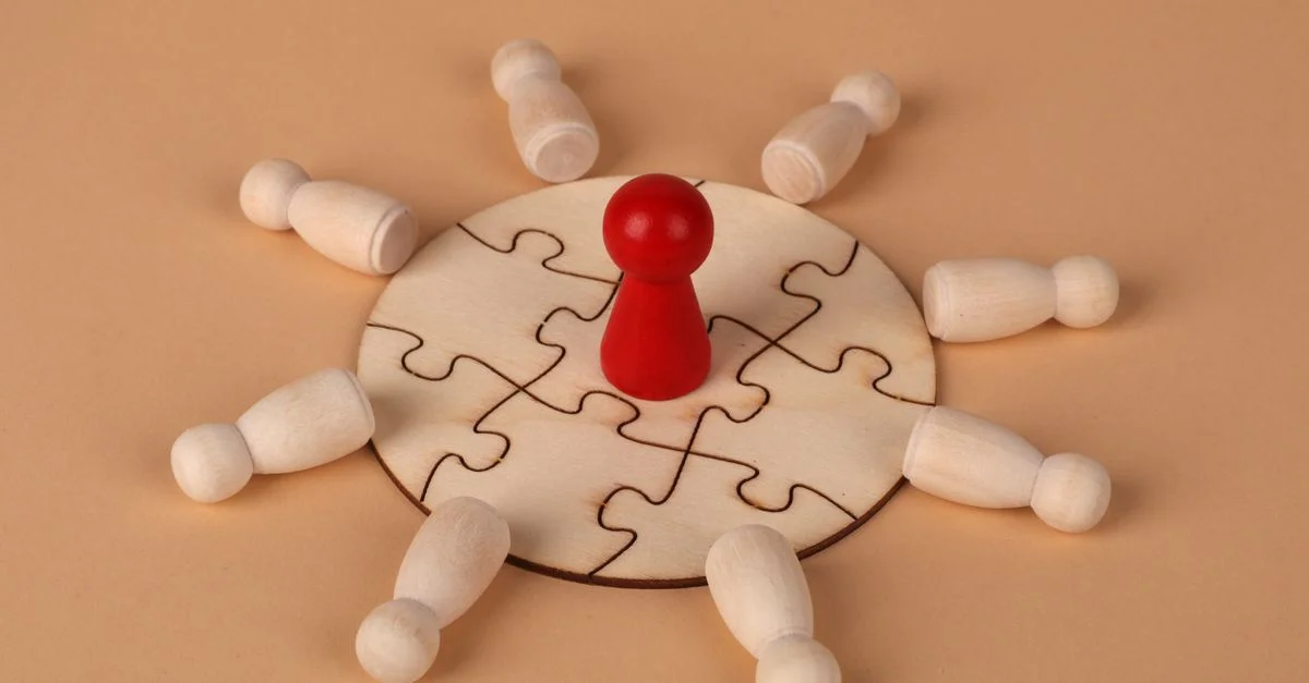 Puzzle en bois avec un pion rouge symbolisant les dynamiques de leadership et de travail d'équipe.
