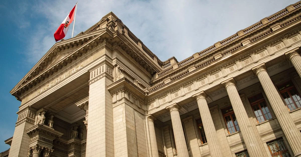 Grand bâtiment gouvernemental néoclassique avec drapeau péruvien à Lima, Pérou, sous un ciel bleu.