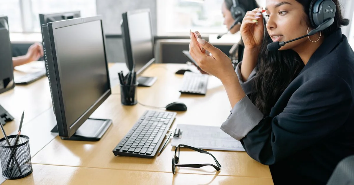 Femme sud-asiatique fournissant un support client dans un environnement de bureau moderne, équipée d'un casque.