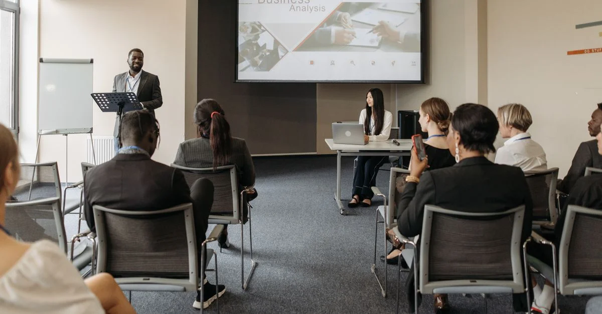 Un groupe divers d'adultes assistent à une présentation dans un cadre de salle de conférence.