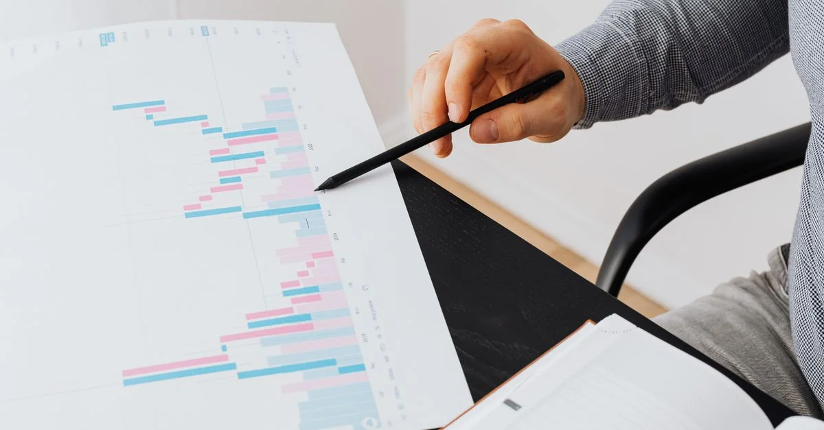 Gros plan sur une personne analysant un graphique coloré avec un stylo dans un bureau moderne.