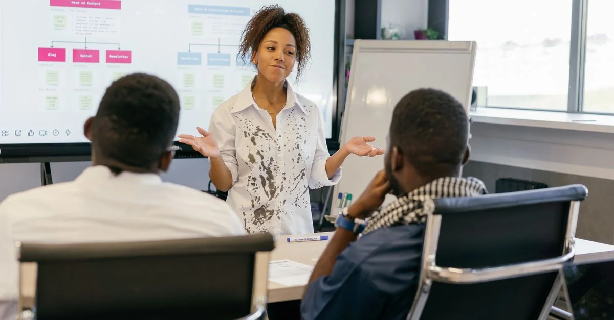 Une femme dirige une réunion d'équipe dans un bureau moderne en utilisant des présentations numériques.