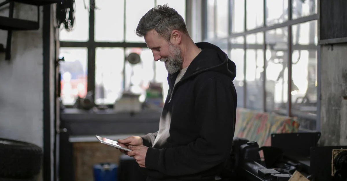 Homme barbu travaillant avec une tablette dans un atelier industriel.